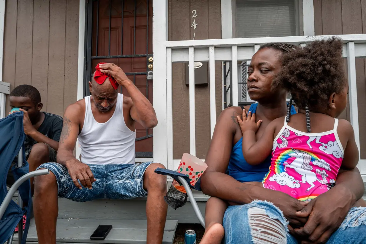 The Coleman family sit together on their front porch as they get some air in Houston, Texas.