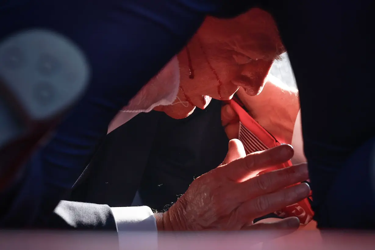 Former President Donald Trump is shown covered by US Secret Service agents after a shooting incident during a rally in Butler, Pennsylvania, on July 13.