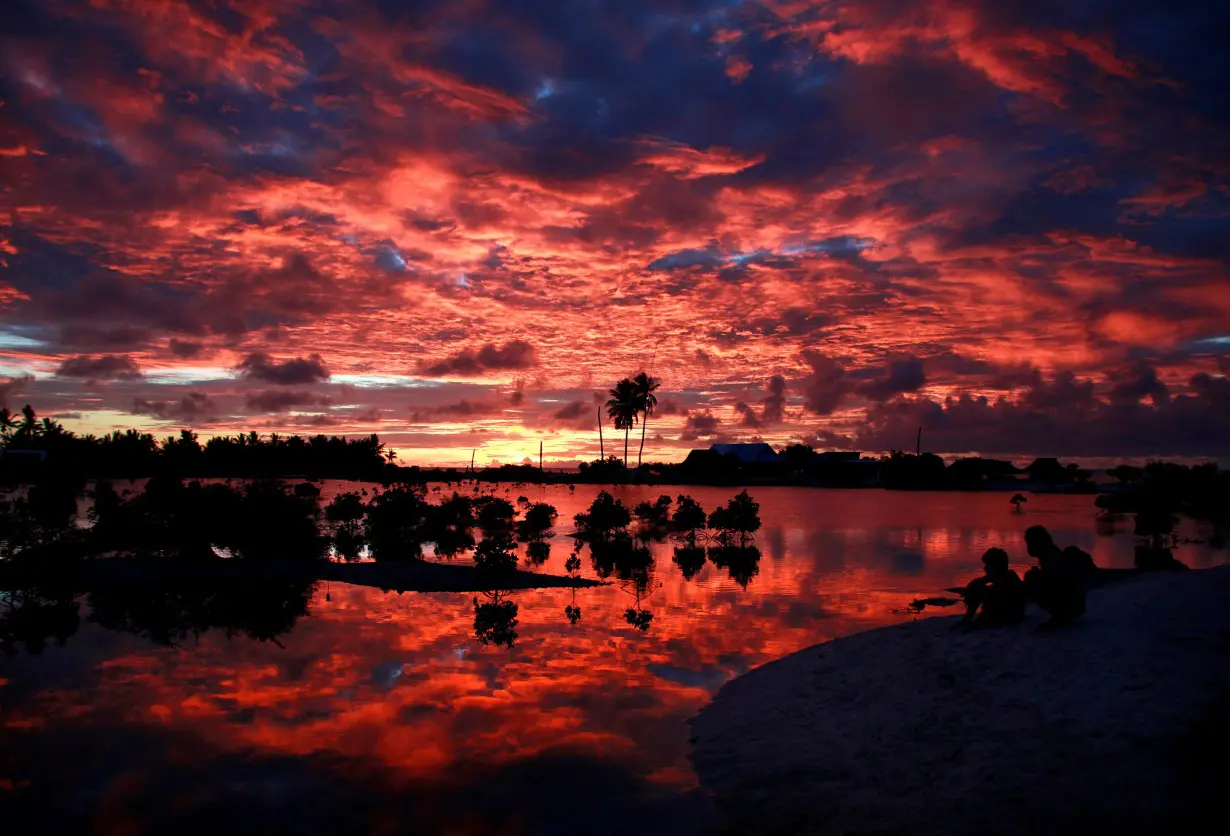 FILE PHOTO: Villagers watch the sunset over a small lagoon near the village of Tangintebu on South Tarawa in the central Pacific island nation of Kiribati