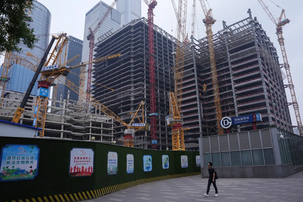 Person walks past a construction site in Beijing's Central Business District (CBD)