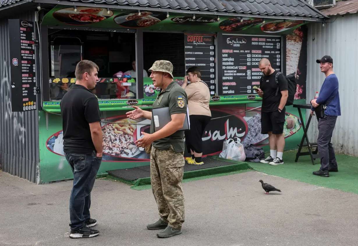 A recruiters officer with the call sign 'Fantomas' checks papers of men and hands out military summonses in Kyiv