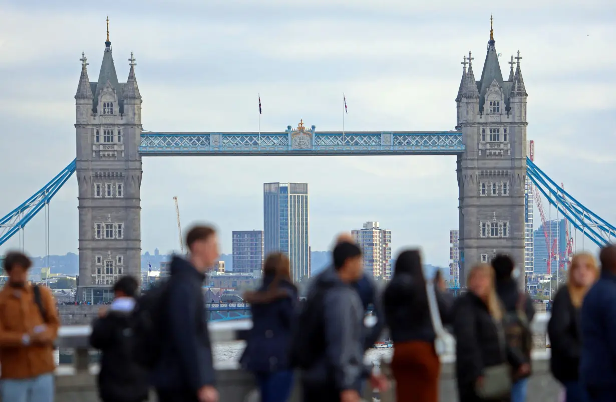 FILE PHOTO: People walk over London Bridge looking at a view of Tower Bridge in the City of London