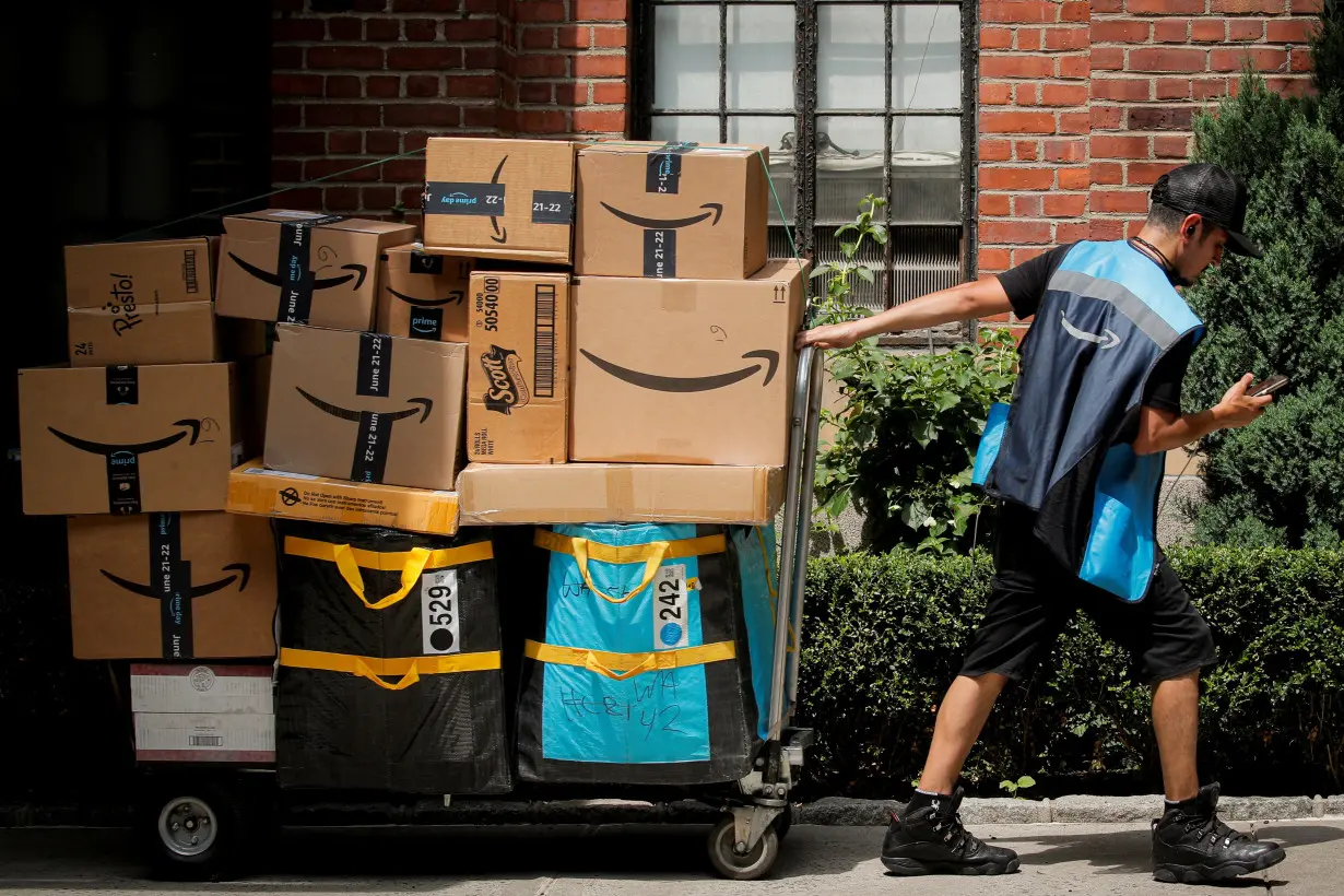 An Amazon delivery worker pulls a delivery cart full of packages during its annual Prime Day promotion in New York