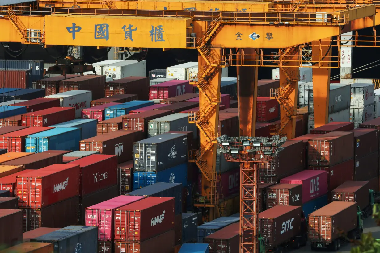 FILE PHOTO: Trucks wait to be loaded on with containers at a port in Keelung