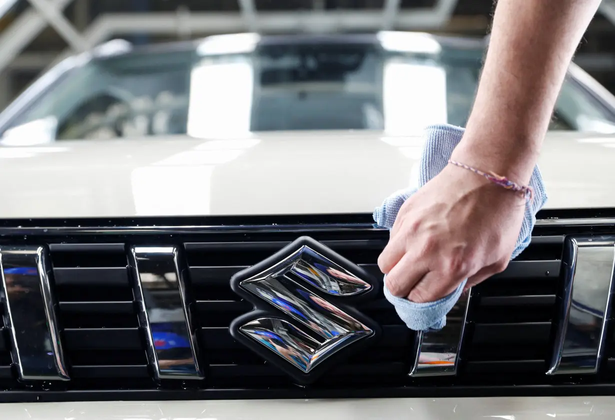 FILE PHOTO: An employee cleans the logo of Suzuki in the Hungarian plant of Japanese car maker Suzuki in Esztergom