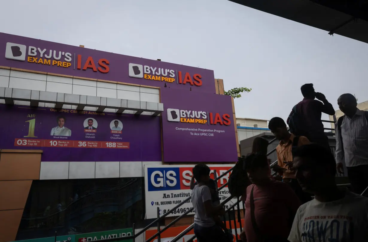 People walk past an advertising hoarding of Byju's, an Education Technology company and one of India's biggest startup, outside one of its branch in New Delhi