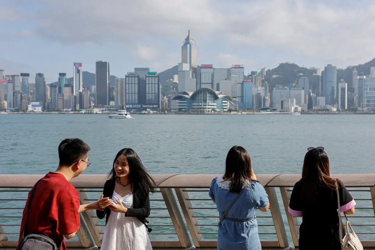 FILE PHOTO: Mainland Chinese tourists take photo of the skyline of buildings at Tsim Sha Tsui, in Hong Kong