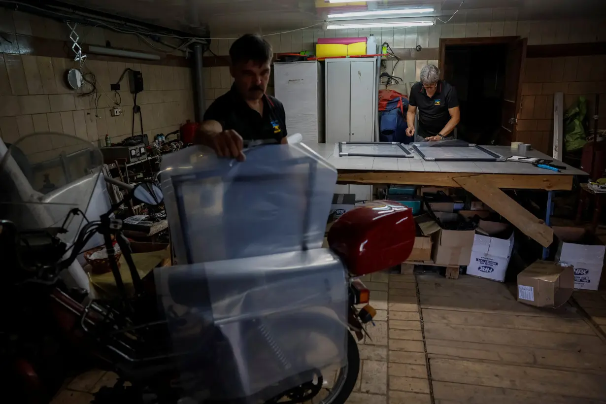 Volunteers of a charitable organisation replace broken by Russian military attacks windows with special frames, in Donetsk region