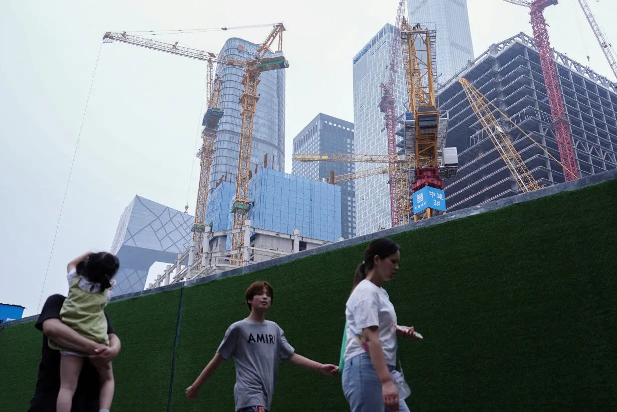 FILE PHOTO: People walk past a construction site in Beijing's Central Business District (CBD)