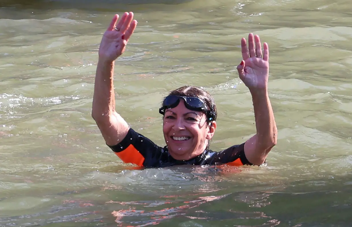 Paris Mayor Anne Hidalgo (R) swims in the Seine River, in Paris on July 17, to demonstrate that the river is clean enough to host the outdoor swimming events at the Paris Olympics later this month.