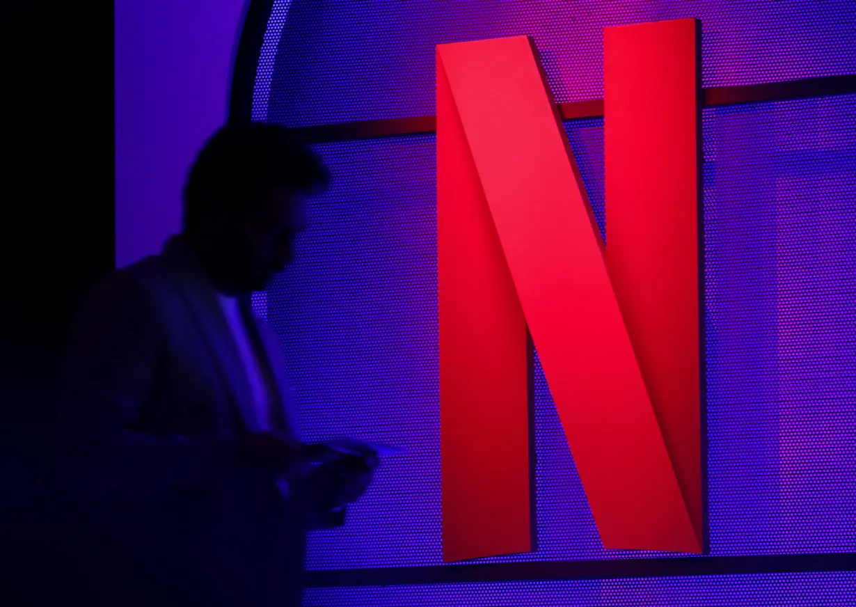 FILE PHOTO: A man stands next to a logo of Netflix during an event in Mumbai