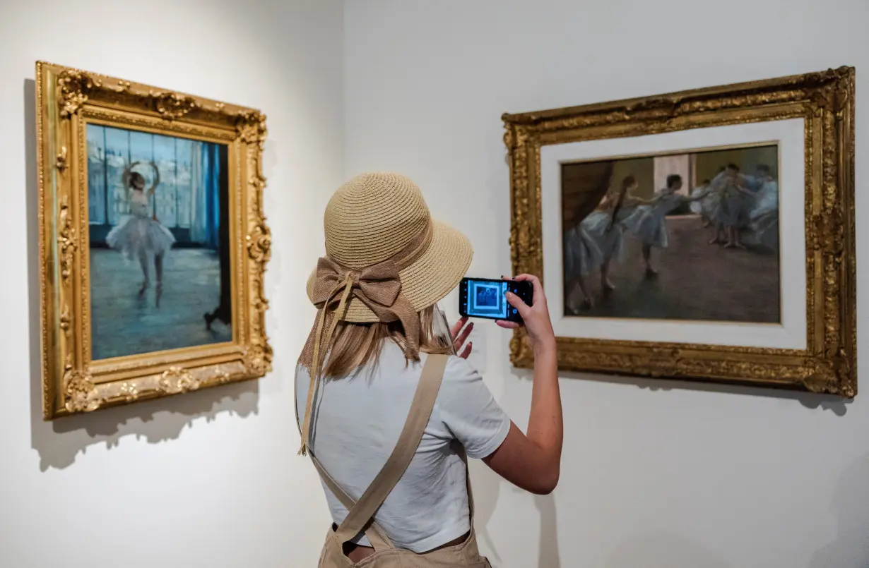 A woman takes a picture of a painting during the 