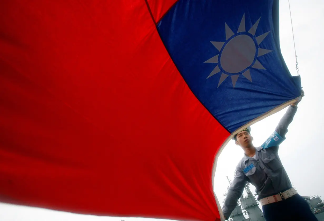 FILE PHOTO: A sailor holds a Taiwan flag on the Navy's 124th fleet Lafayette frigate during a model units tour in Kaohsiung