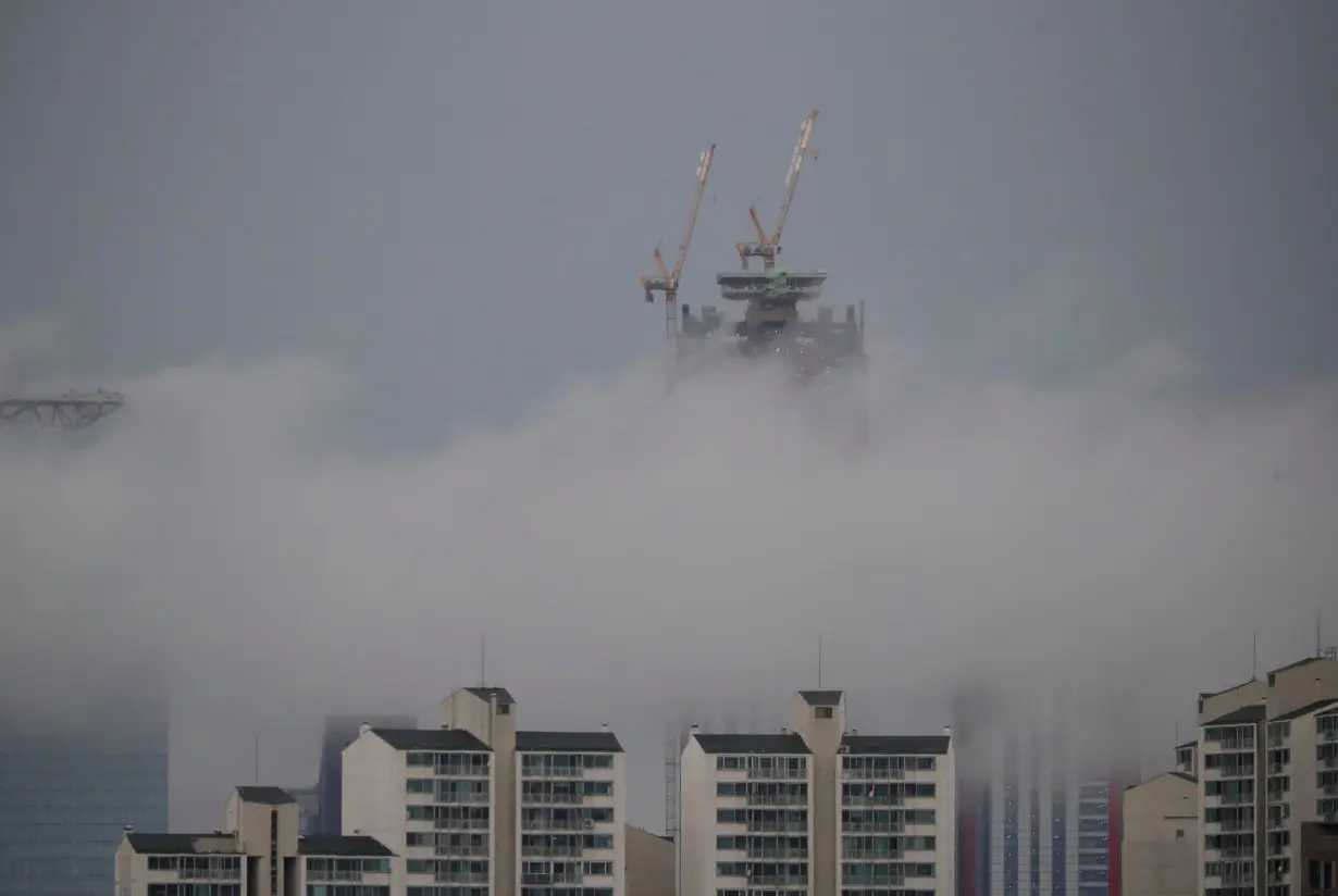 A building which is currently under construction is seen above a fog during a rainy day in Seoul