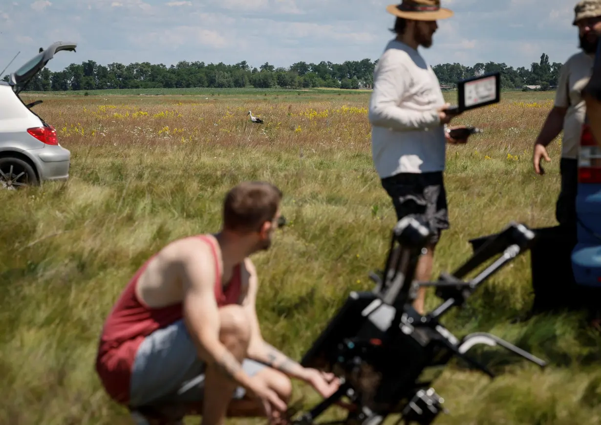 A stork walks across a field as employees of Swarmer company prepare the AI-enabled drone for flight in Kyiv region