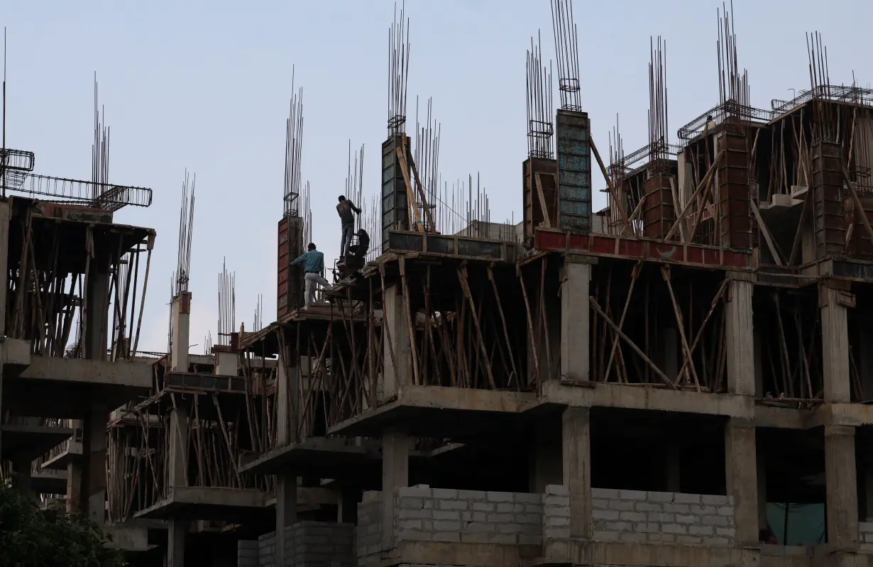 Workers fasten iron rods together at the construction site of a residential building of Pradhan Mantri Awas Yojana in Ahmedabad