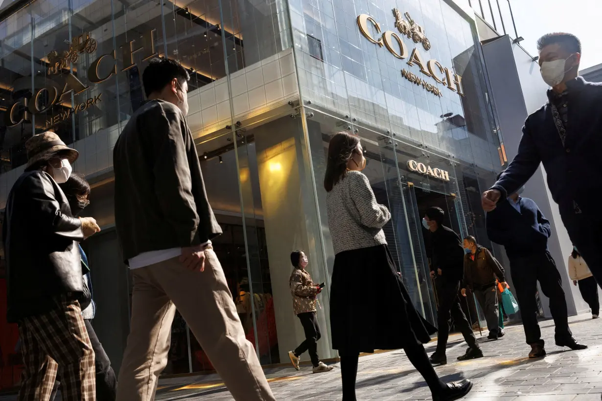 FILE PHOTO: People walk past a store of the Coach luxury fashion retailer in a shopping district in Beijing