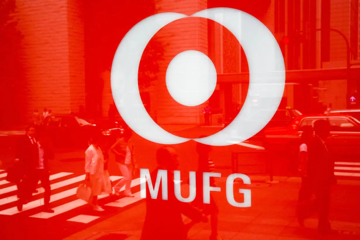 People are reflected in the logo of Mitsubishi UFJ Financial Group's bank of Tokyo-Mitsubishi UFJ in Tokyo