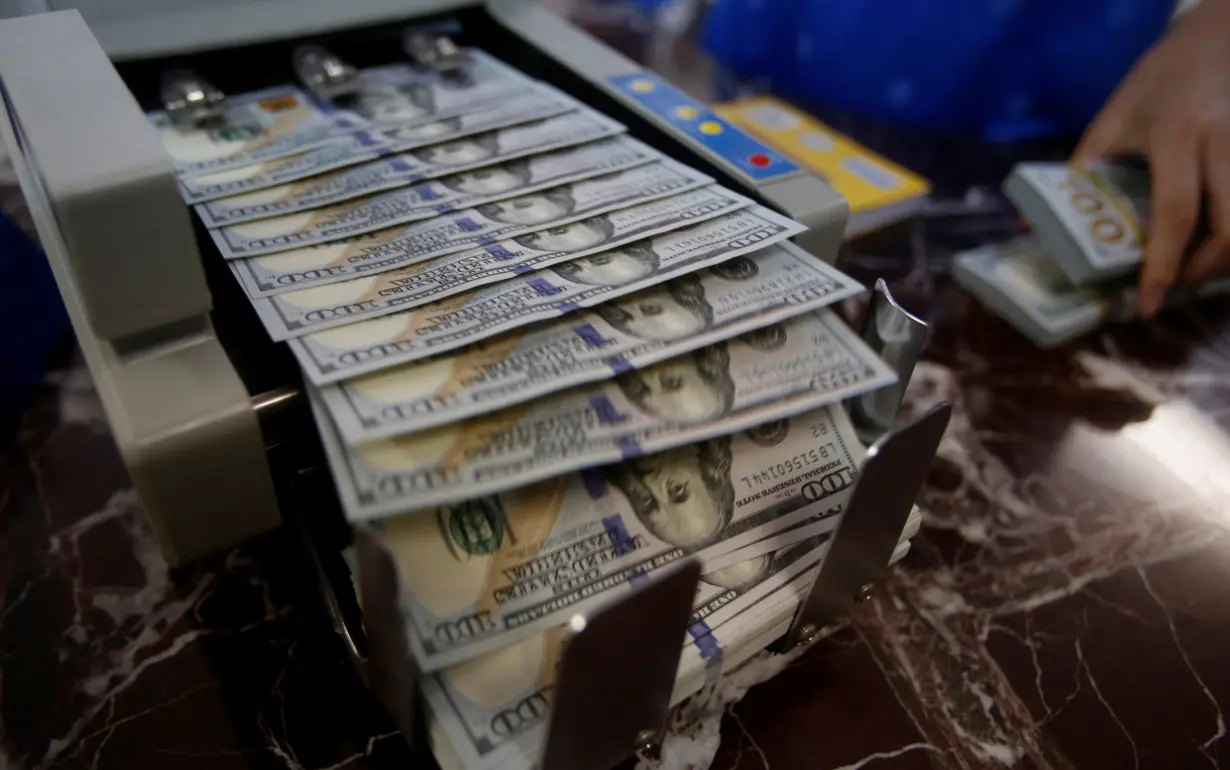 FILE PHOTO: An employee of a bank counts US dollar notes at a bank branch.