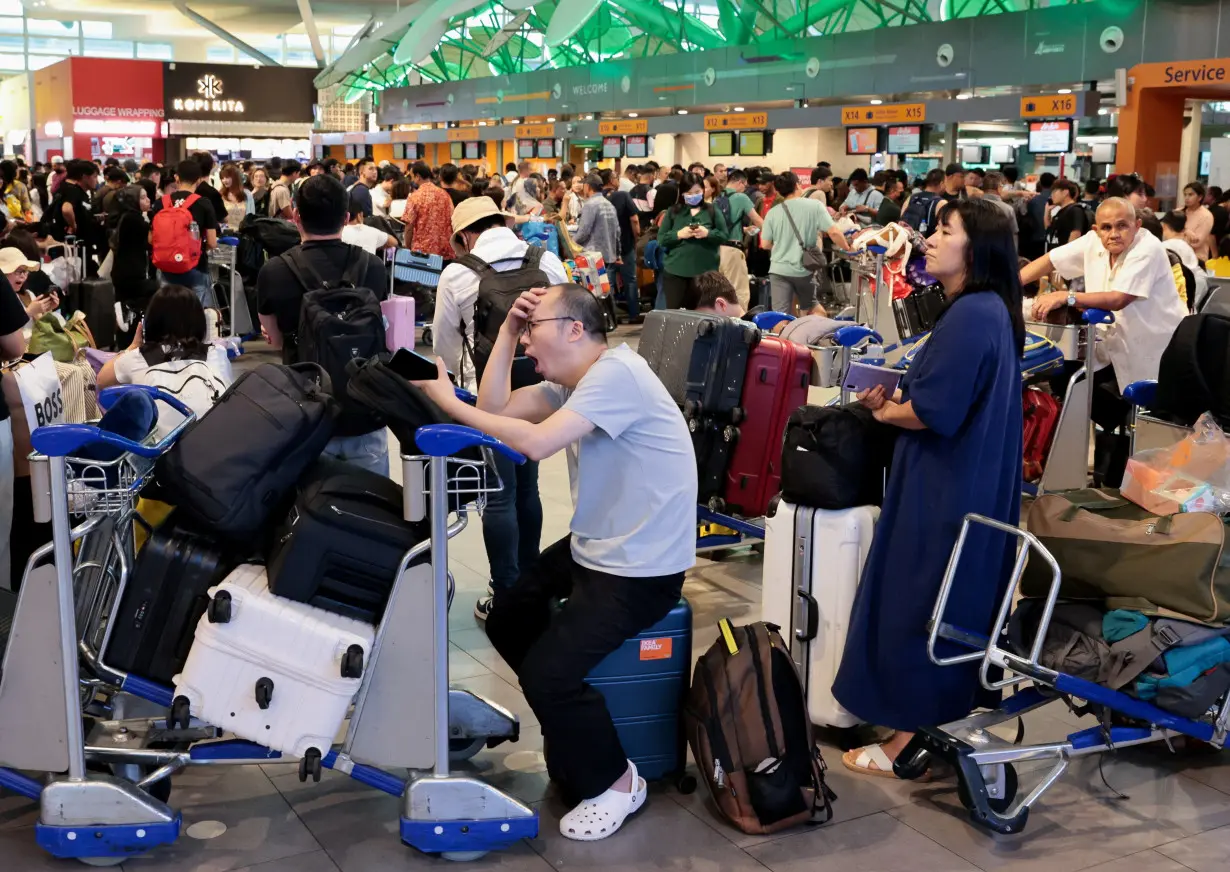 Passengers wait to be checked in manually at Kuala Lumpur International Airport, after global IT outage, in Sepang