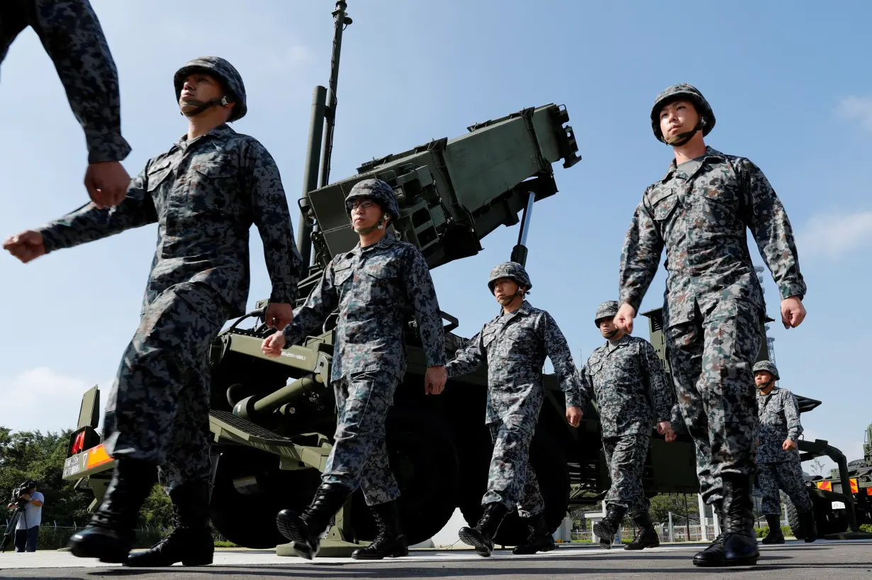 FILE PHOTO: Japan Self-Defense Forces (JSDF) soldiers walk past a Patriot Advanced Capability-3 (PAC-3) missile unit after Japan's Chief Cabinet Secretary Yoshihide Suga (L) reviews the unit at the Defense Ministry in Tokyo