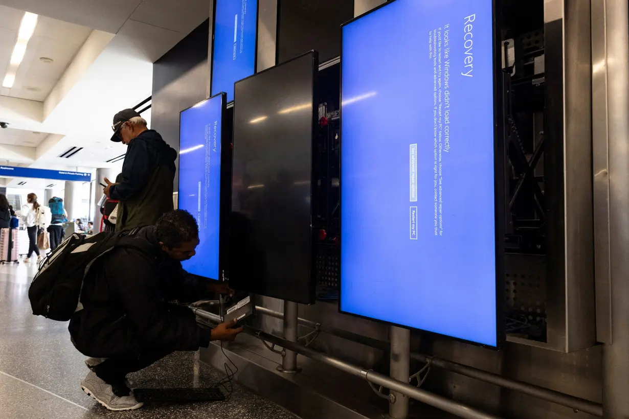 A Delta technician works on a set of screens displaying a blue page and reading 