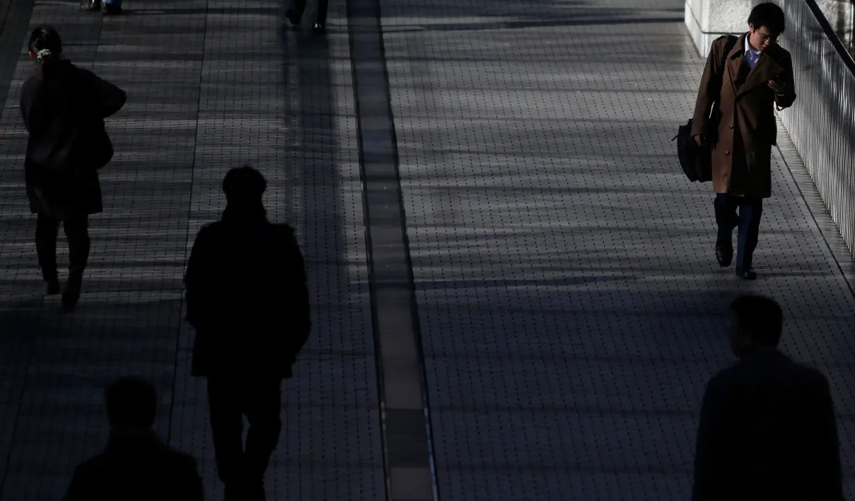 Pedestrians walk on an overpass at a business district in Tokyo