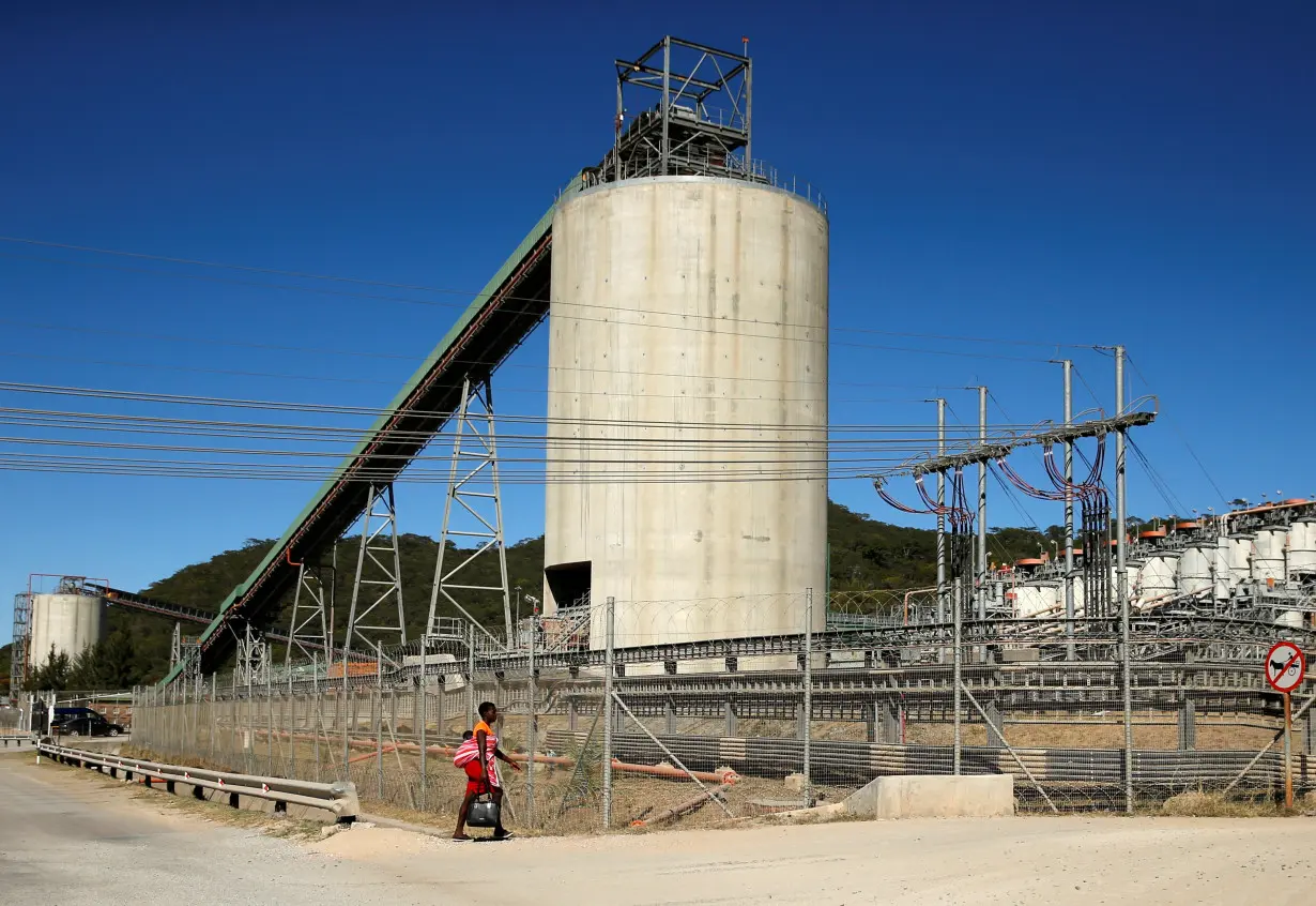 A woman walks past Anglo American Platinum's Unki mine in Shurugwi