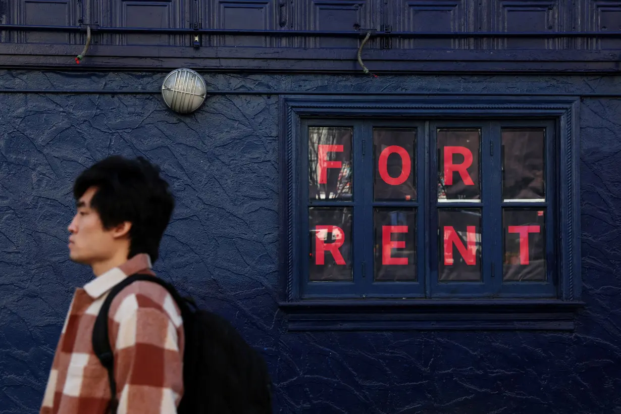 FILE PHOTO: A man walks by as sign advertising real estate for rent in the SoHo area of New York City