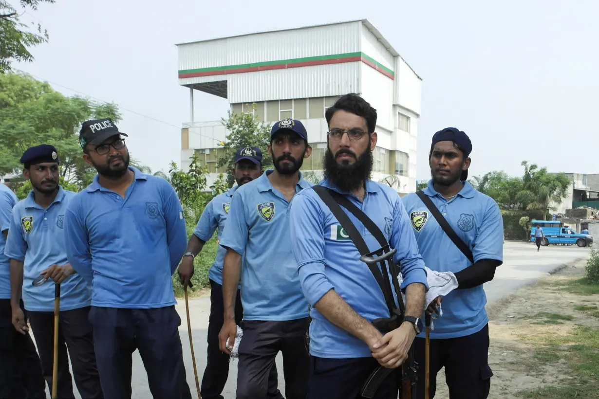 Police officers stand with the Pakistan Tehreek-e-Insaf (PTI) party secretariat building in the background, in Islamabad