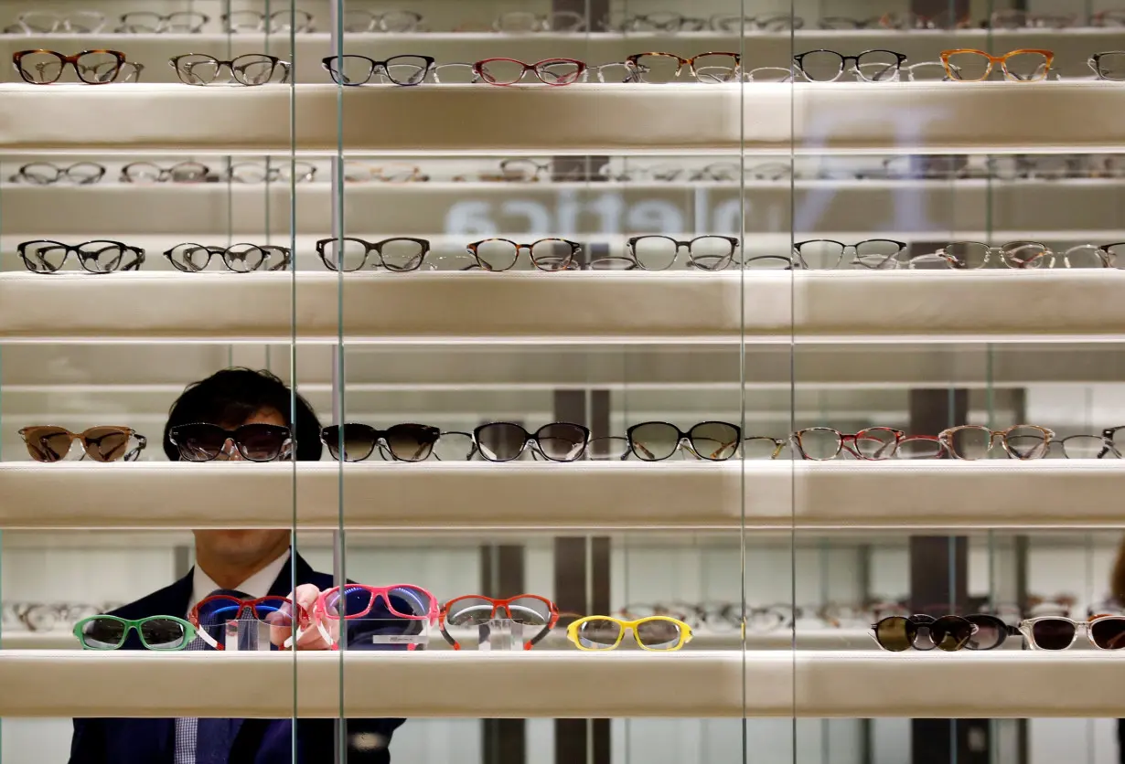 A store assistant adjust eyewear on display in Singapore