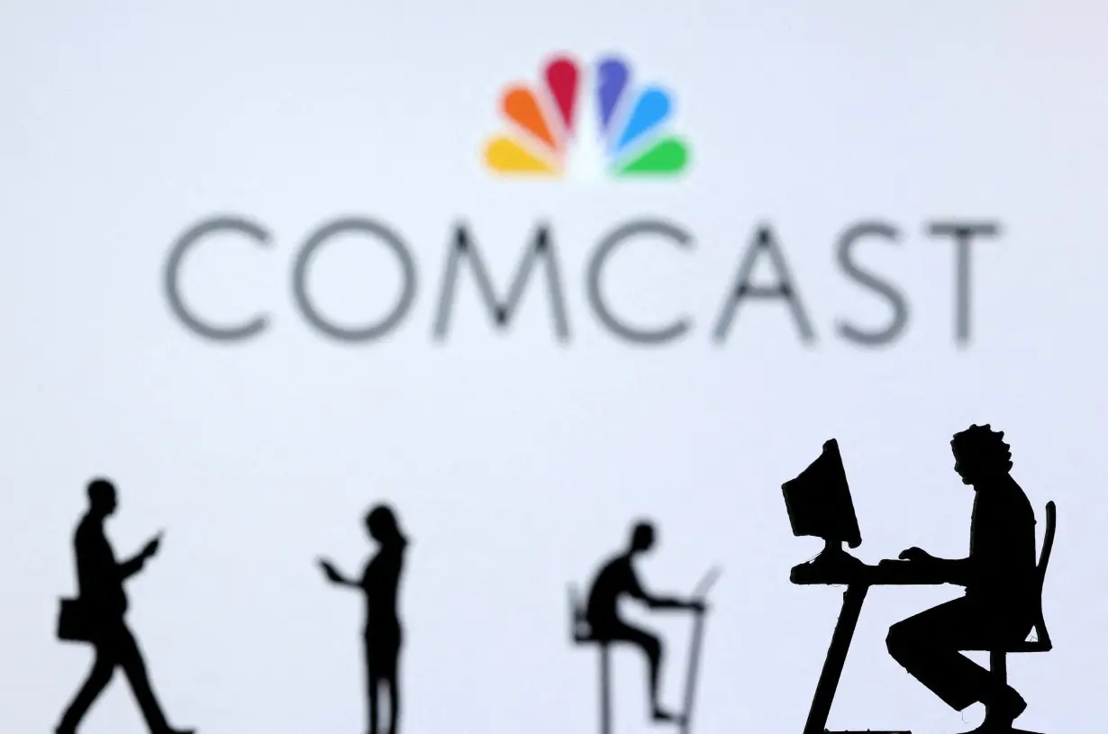 FILE PHOTO: Illustration shows small toy figures with laptops and smartphones in front of displayed Comcast logo