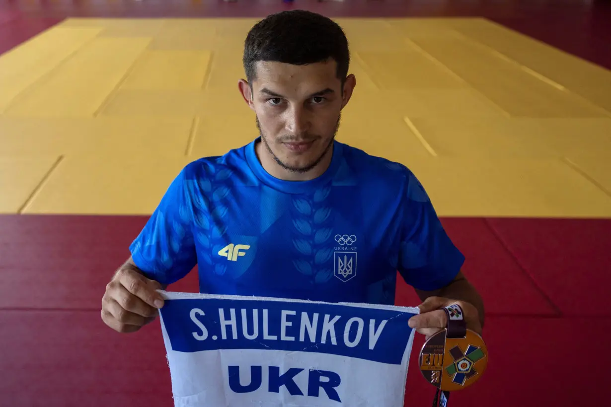 Vadym Chernov, a childhood friend and judo partner of Stanislav Hulenkov, who was killed fighting against Russia's invasion, holds the name tag of his late friend and the medal he dedicated to him at their training base in Kyiv