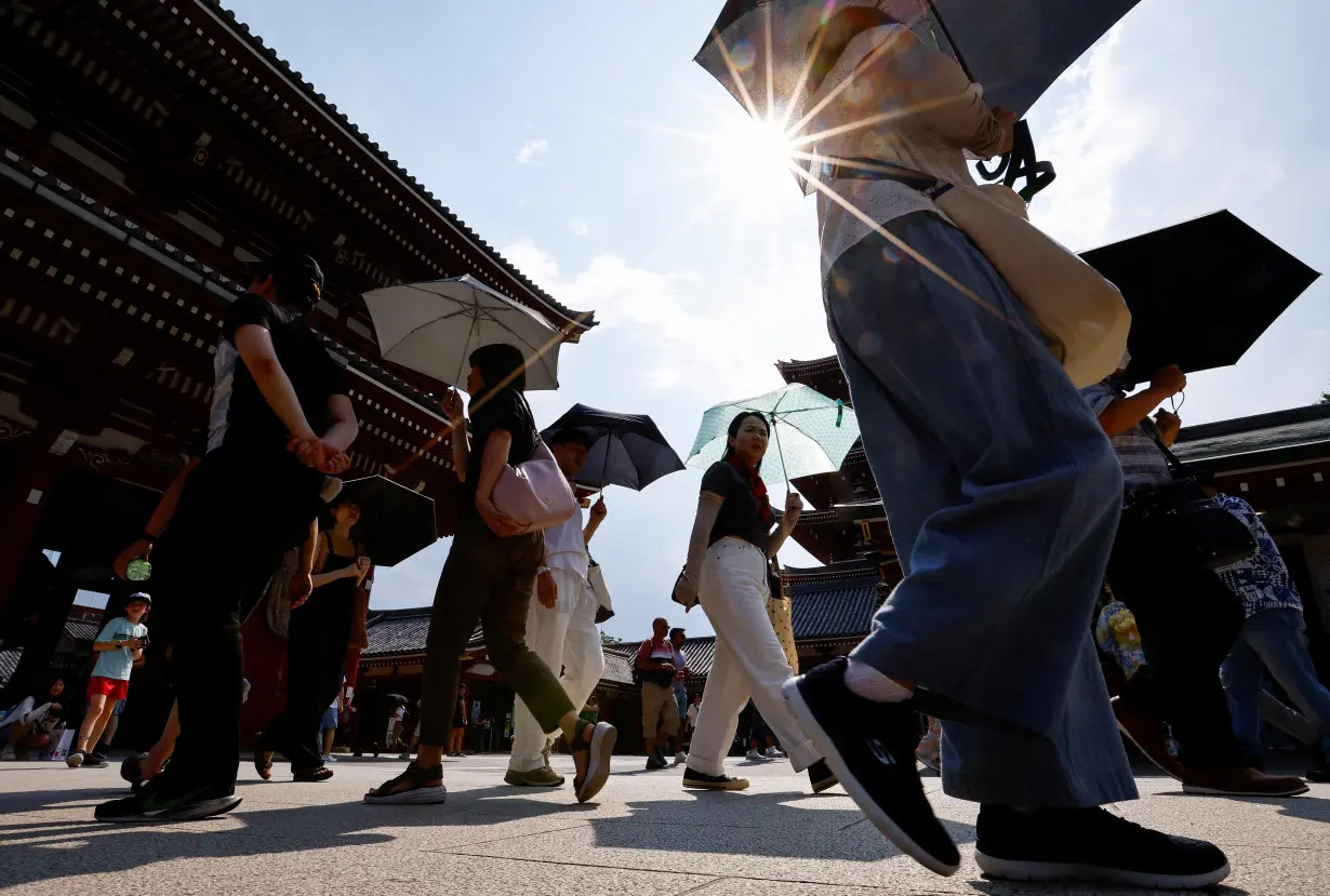 Passersby holding umbrellas walk under a strong sunlight at Sensoji temple as Japanese government issued heat stroke alerts in Tokyo