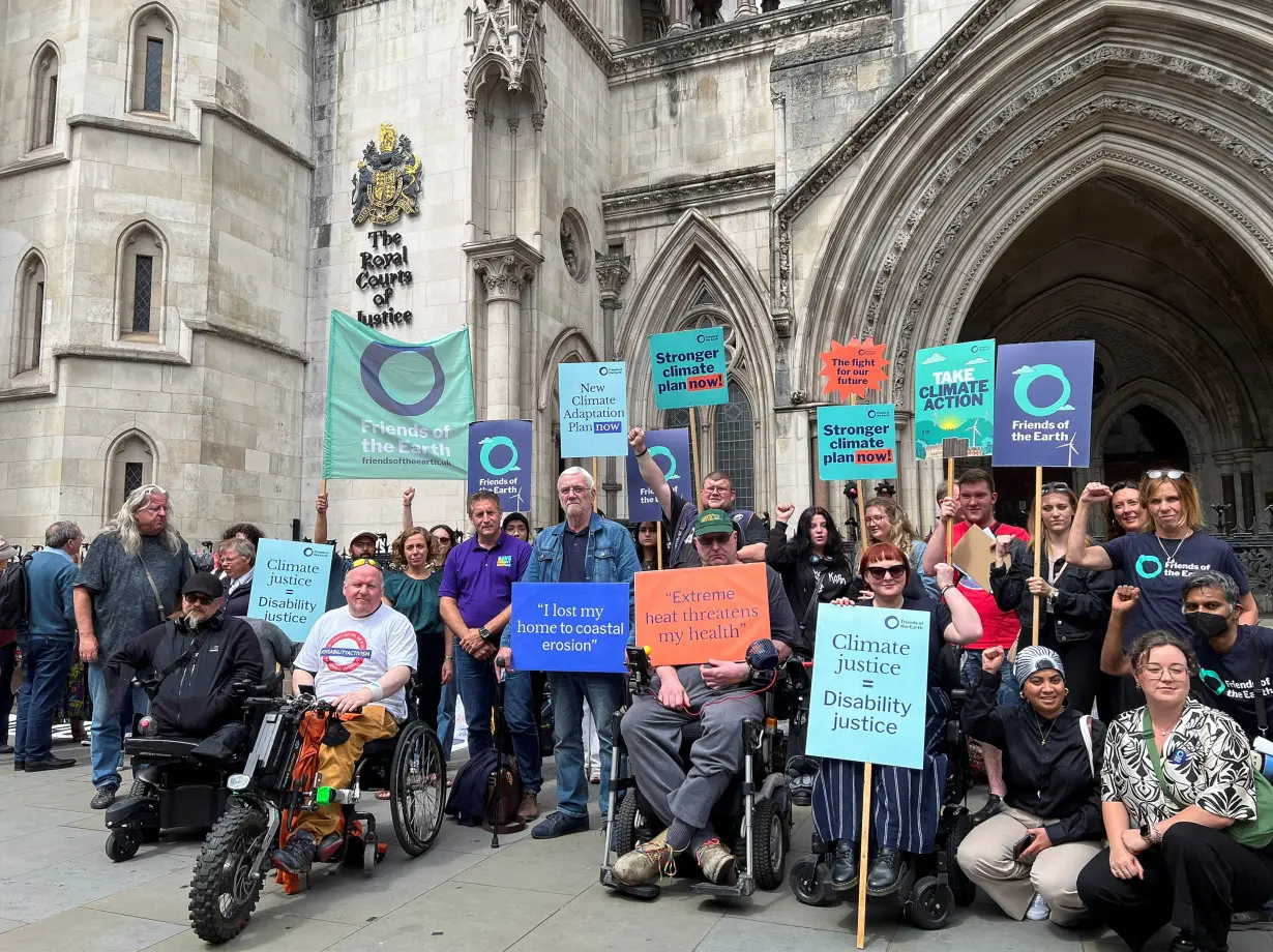 Supporters of environmental group Friends of the Earth hold signs outside the Royal Courts of Justice, in London