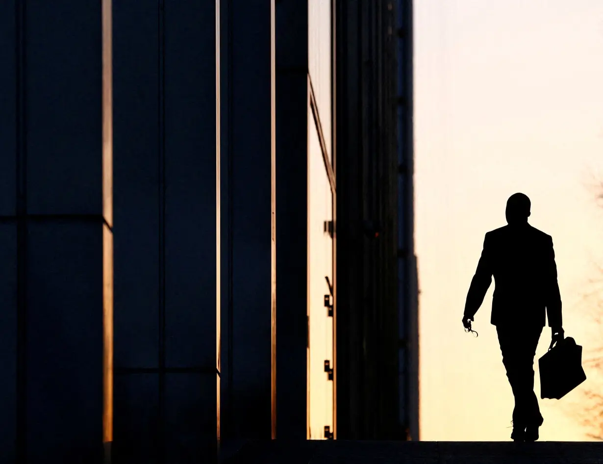 FILE PHOTO: FILE PHOTO: A worker arrives at his office in the Canary Wharf business district in London