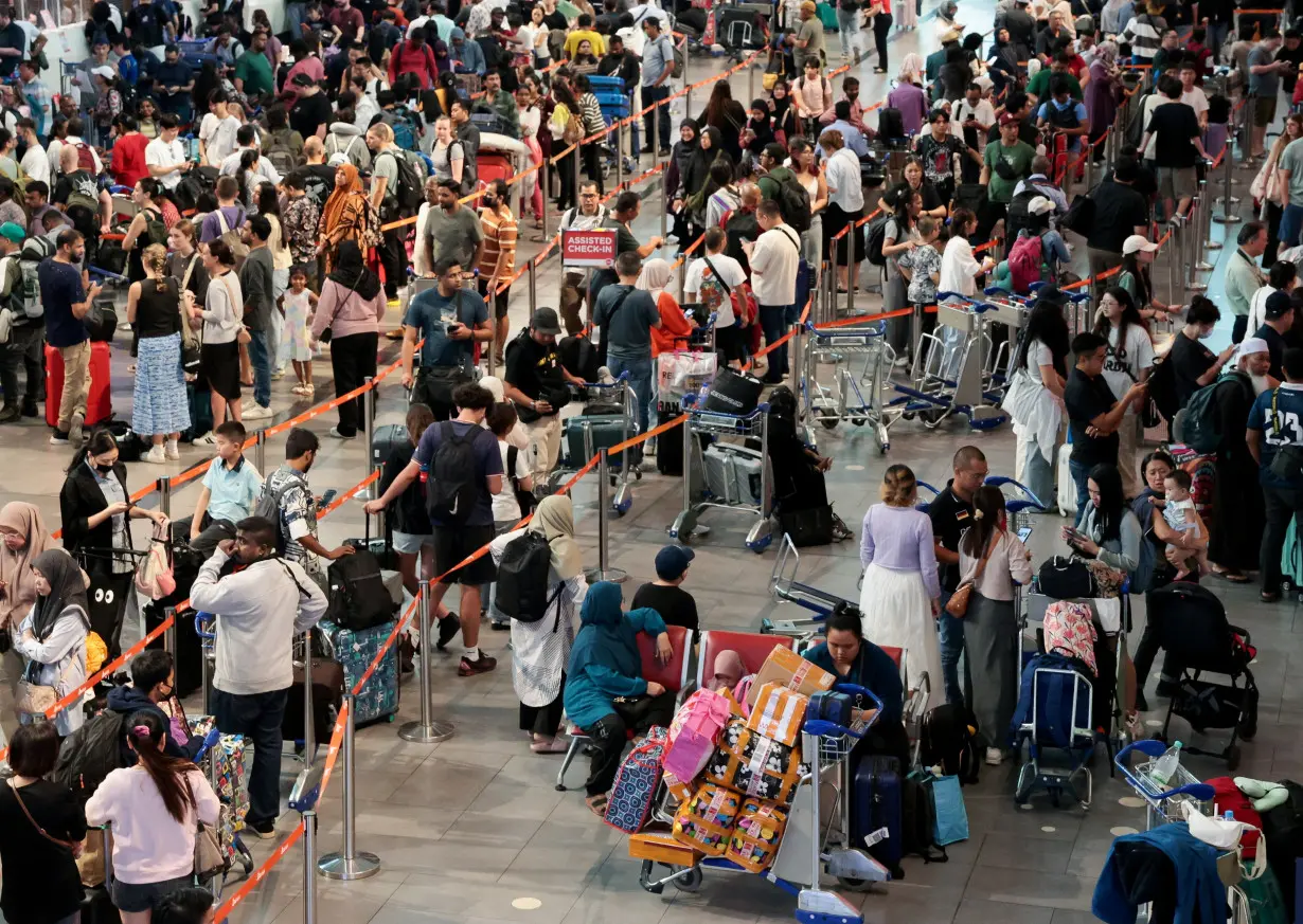 Passengers wait to be checked in manually at Kuala Lumpur International Airport, after global IT outage, in Sepang