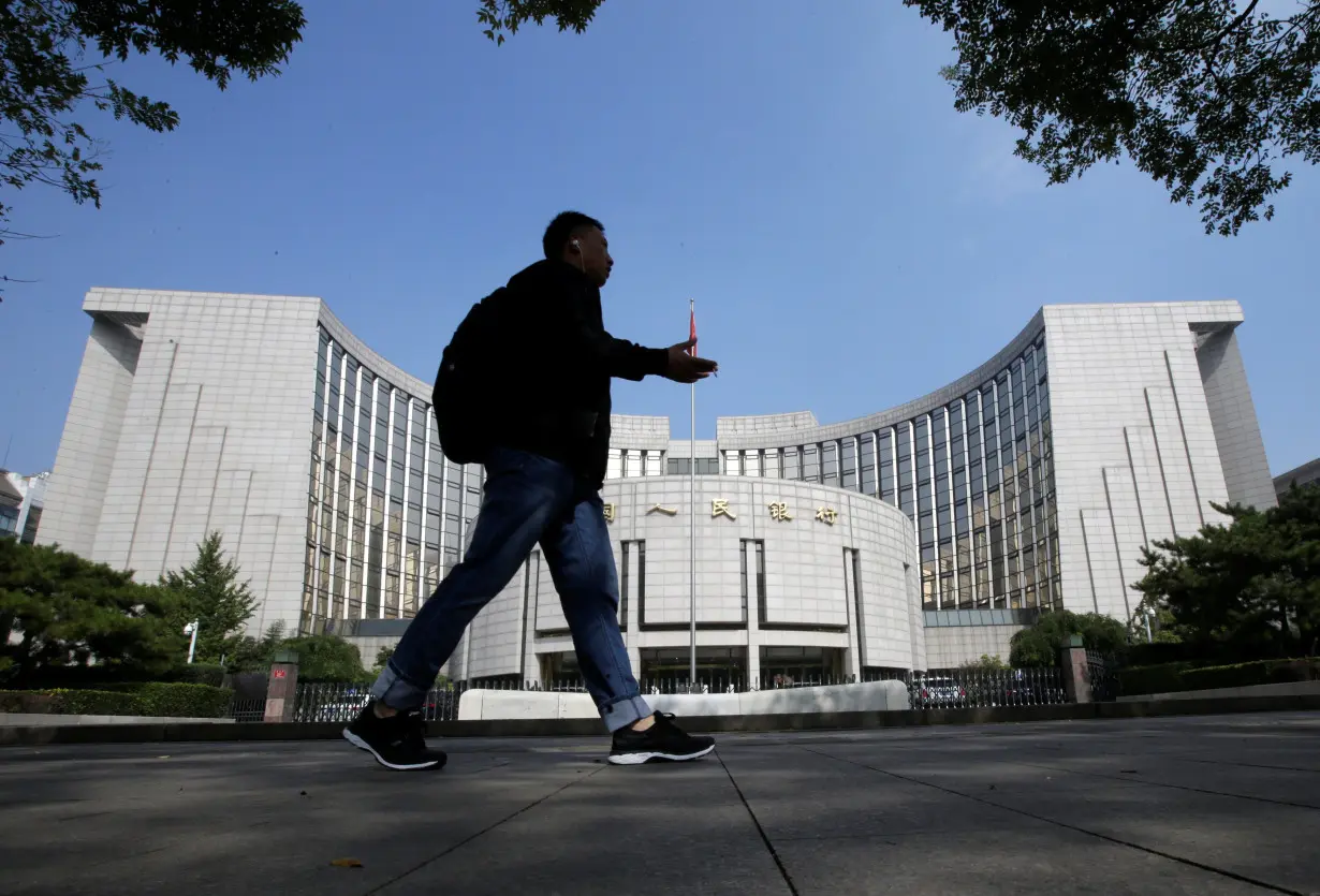 A man walks past the headquarters of the PBOC, the central bank, in Beijing