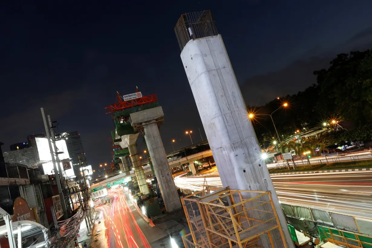 Cars pass Skytrain construction site in Bangkok