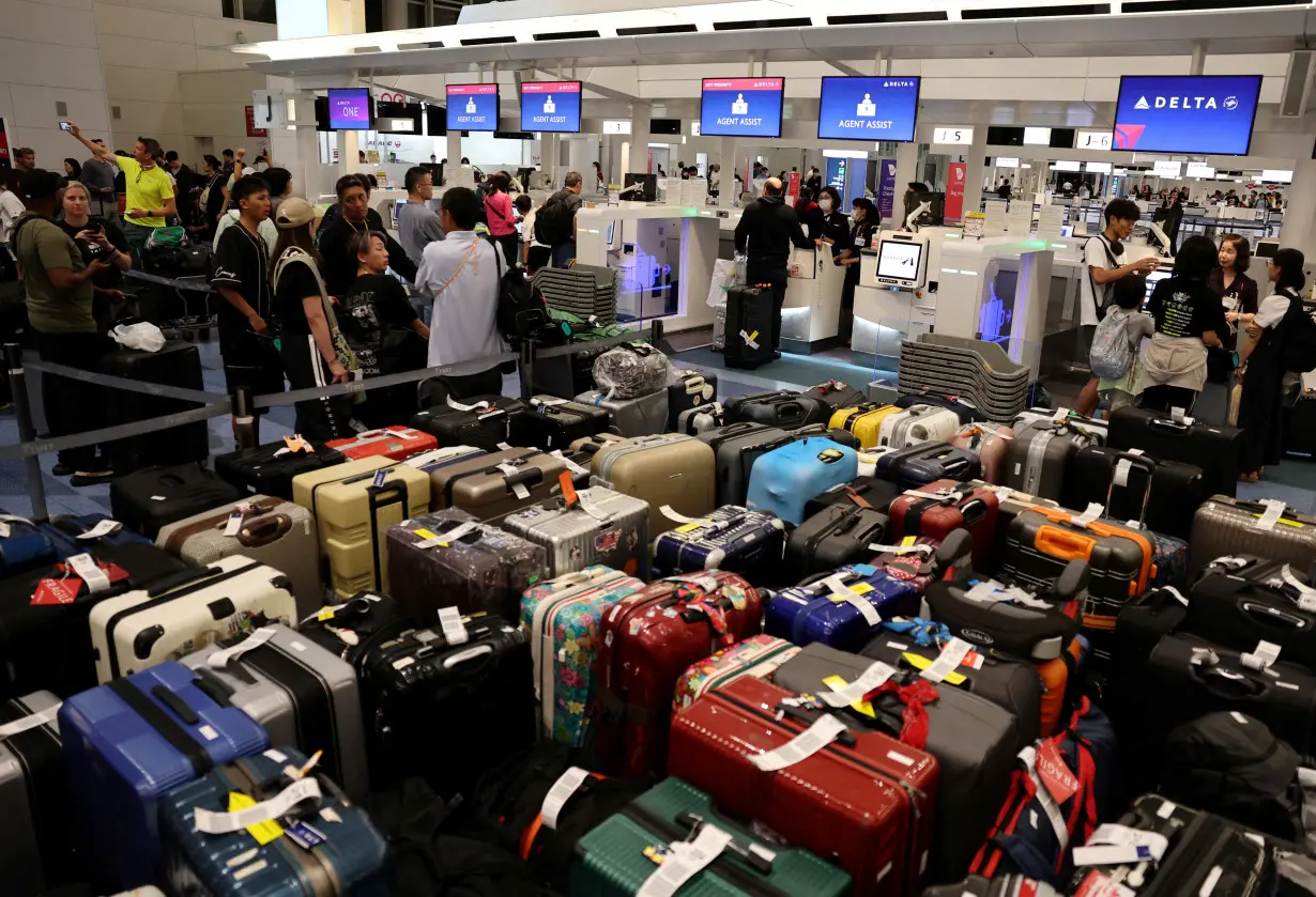 FILE PHOTO: Passengers stands in a line at Delta Airlines' counter following a global IT outage, at Haneda International Airport in Tokyo