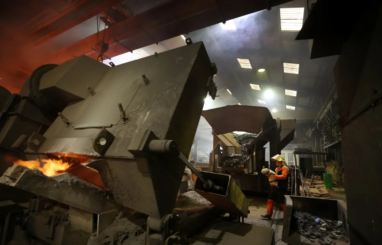 A worker adds a bag of carbon into a furnace full of scrap metal at the United Cast Bar Group's foundry in Chesterfield