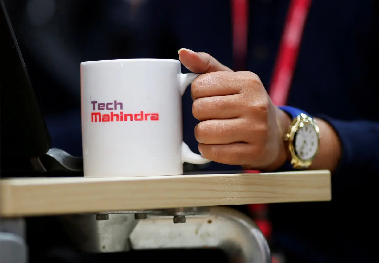 FILE PHOTO: An employee holds a cup as she works at her desk inside the Tech Mahindra office building in Noida