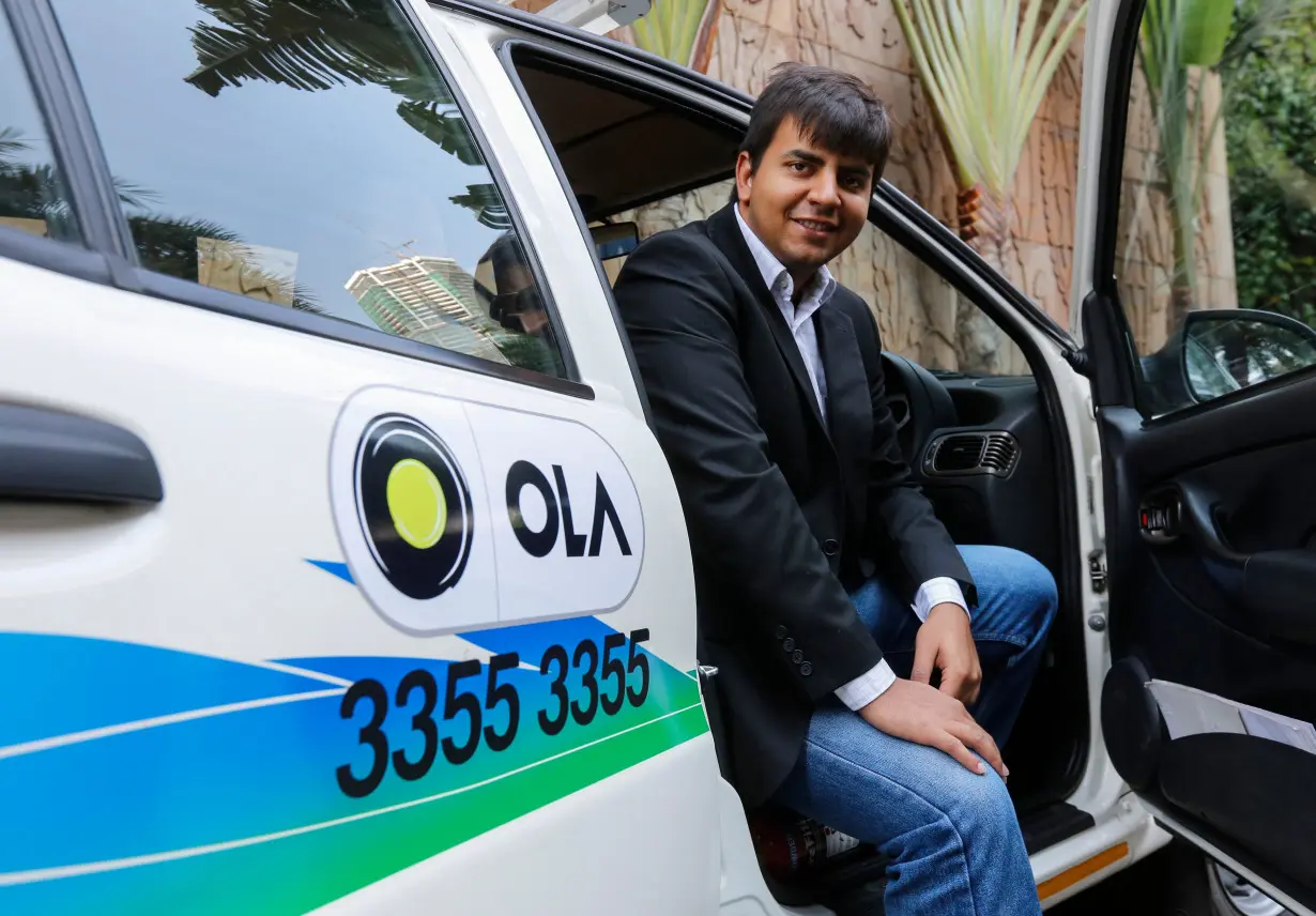 Bhavish Aggarwal, CEO and co-founder of Ola, an app-based cab service provider, poses in front of an Ola cab in Mumbai