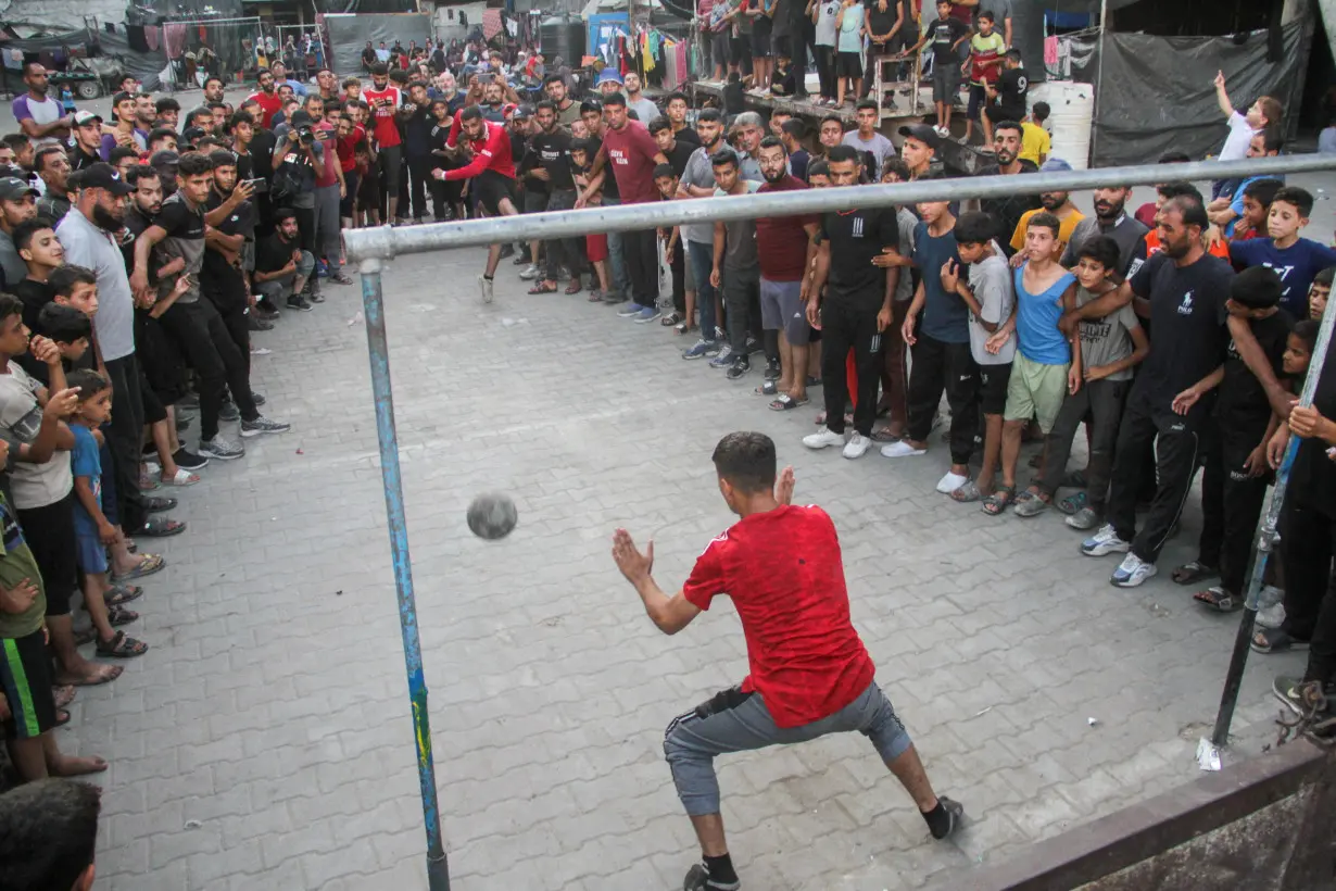 A displaced Palestinian shoots a penalty kick during a soccer match at an UNRWA shelter school, amid Israel-Hamas conflict, in Jabalia in the northern Gaza Strip