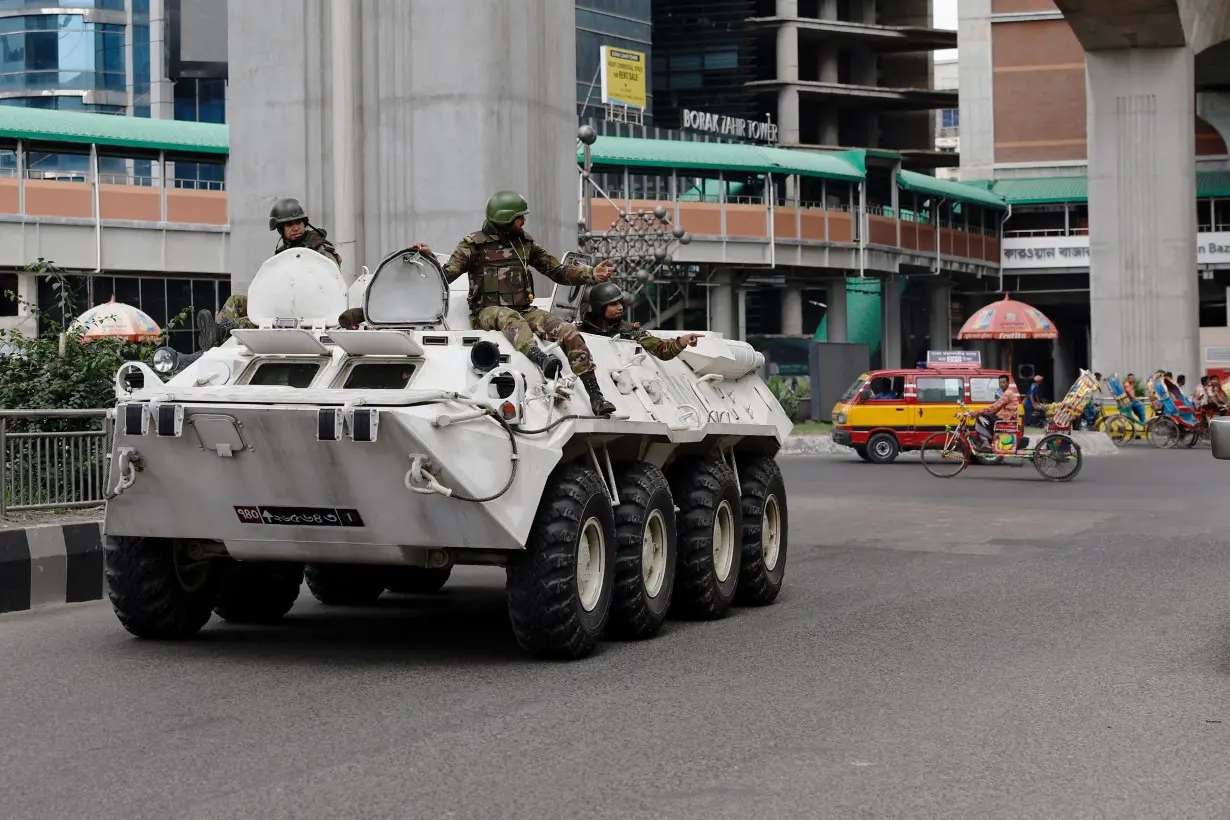 FILE PHOTO: Members of Bangladesh Army gesture as they patrol in an armoured vehicle on the second-day of curfew, in Dhaka