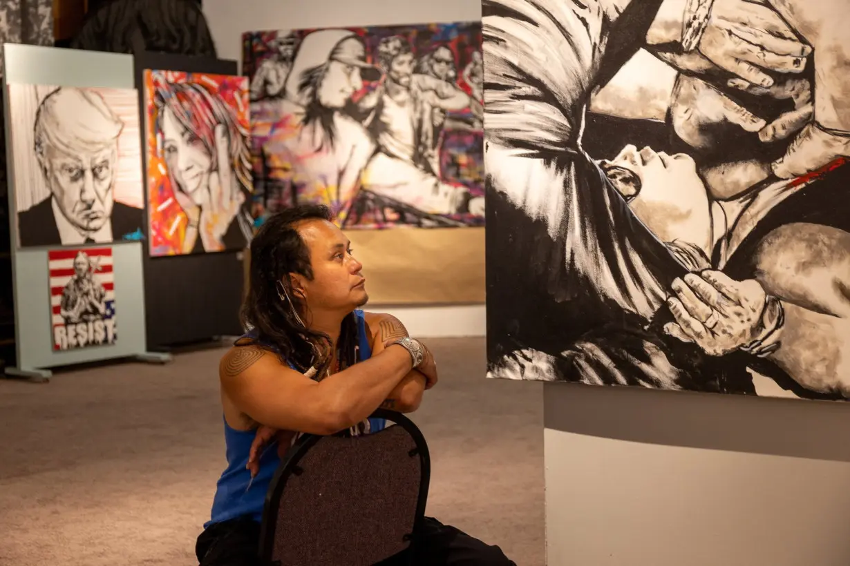 Native American climate activist and artist Jacob Johns poses next to his work, in Santa Fe