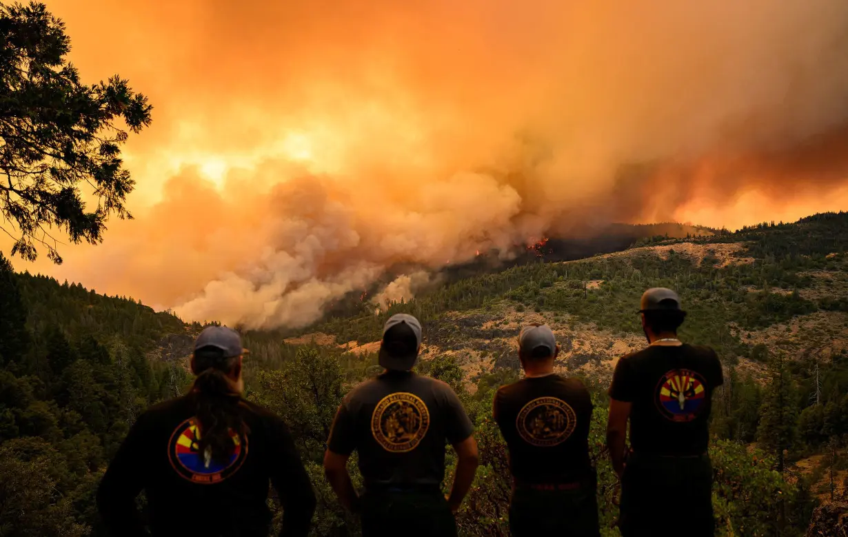 Firefighters watch as flames and smoke move through a valley in the Forest Ranch area of Butte County as the Park Fire continues to burn near Chico, California, on July 26.