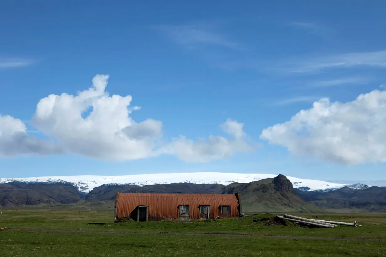 FILE PHOTO: A farm building stands in a field below the Myrdalsjokull glacier that covers the Katla volcano in Evindarholar, Iceland