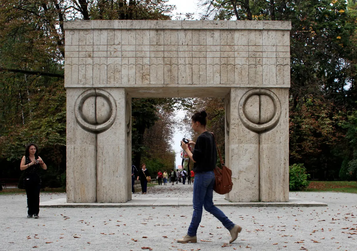 Tourists take pictures of the Gate of the Kiss, a marble sculpture made by Constantin Brancusi, in Targu Jiu