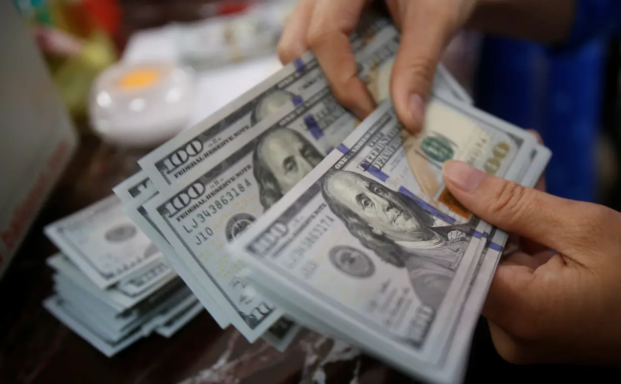 An employee of a bank counts US dollar notes at a branch in Hanoi